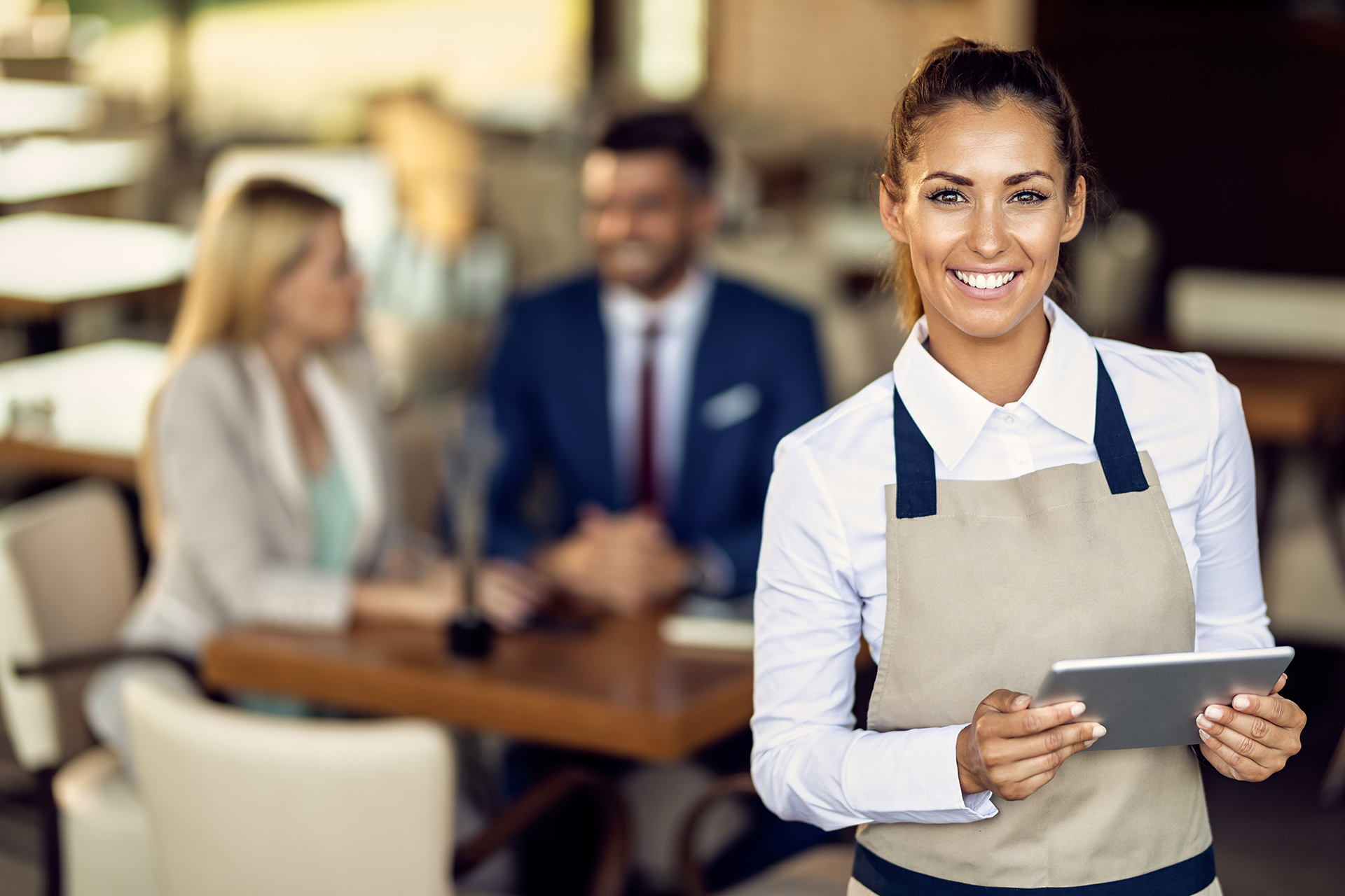 Young happy waitress using touchpad while working in a cafe.