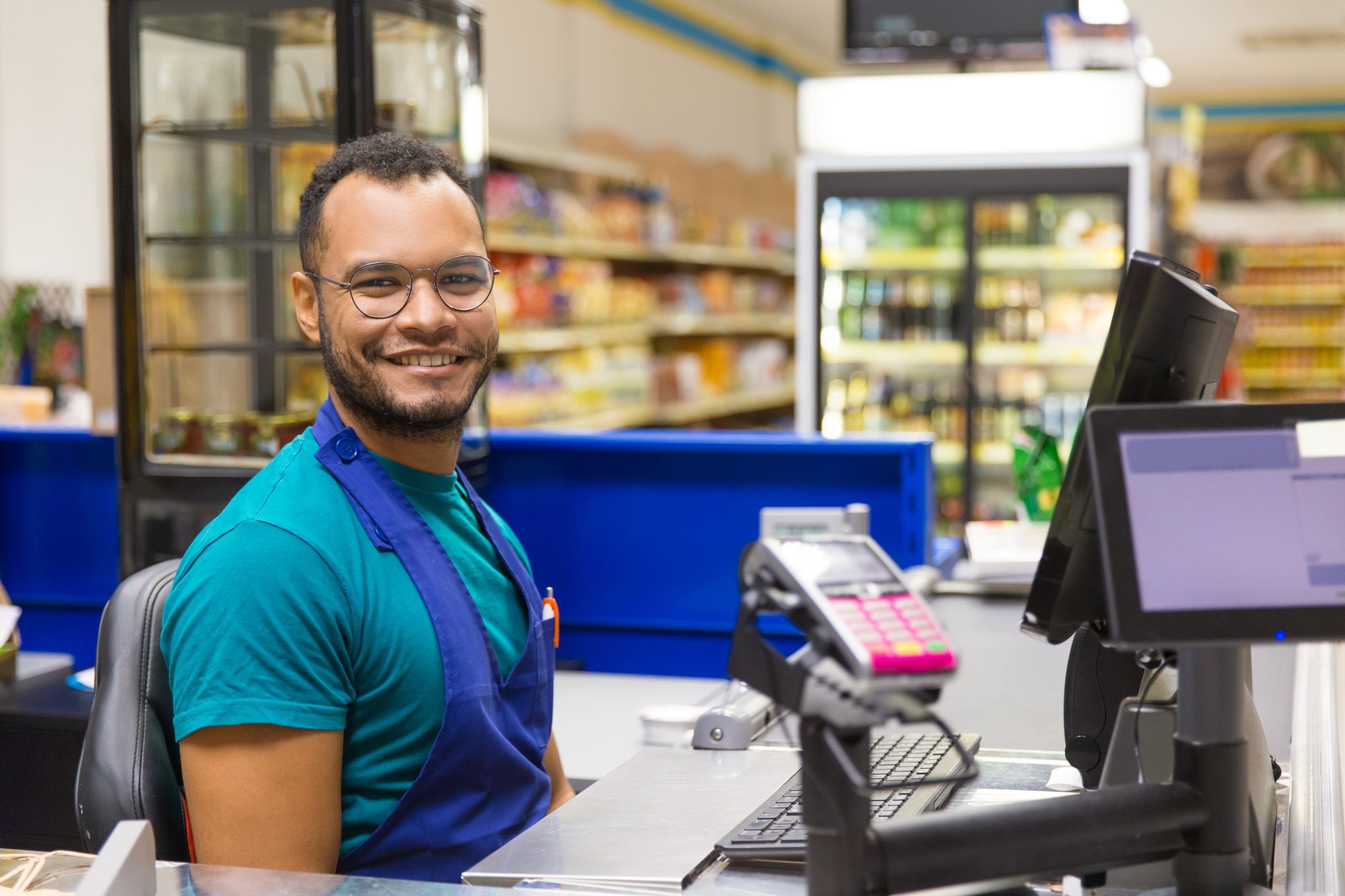 Smiling African American cashier sitting at checkout